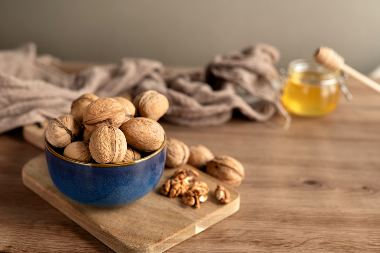 Organic walnuts in shells being shelled into halves on a chopping board
